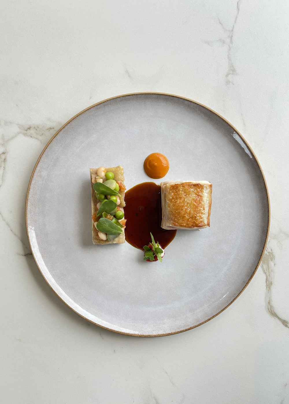 Plat gastronomique avec une présentation artistique sur une assiette blanche.