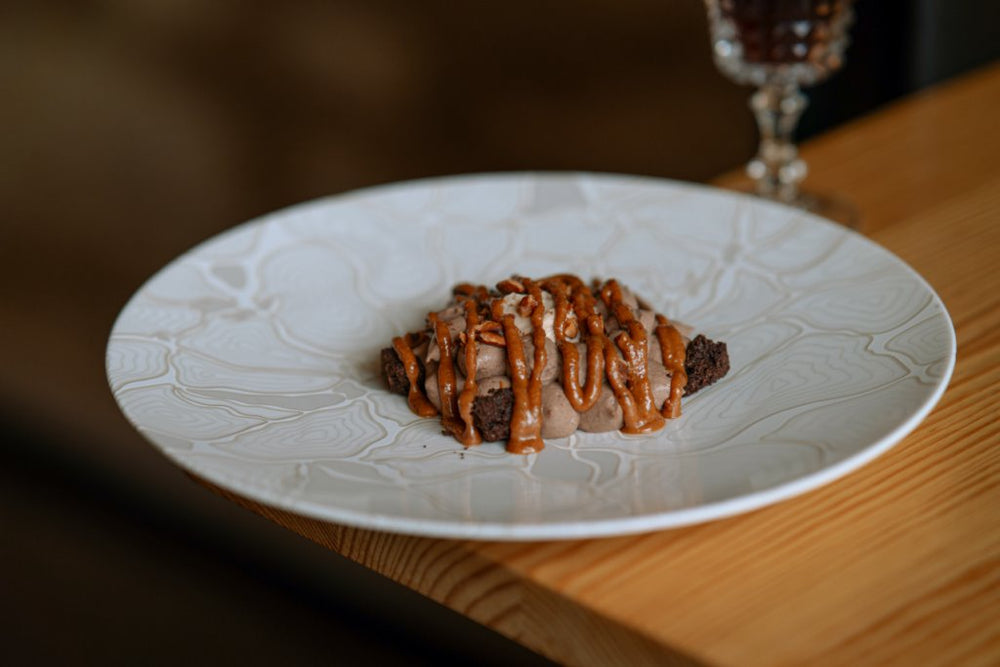 Dessert chocolaté avec une garniture de crème onctueuse et des noix sur une assiette en céramique blanche