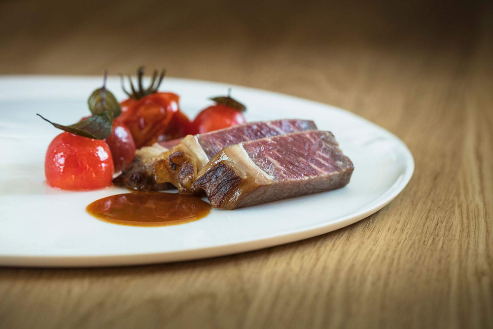 De beaux morceaux de viande saignants, des tomates cerises rôties et un jus de viande