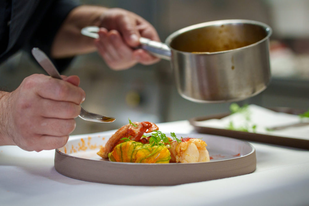 Chef apportant la touche finale à un plat de langouste et de fleur de courgette farcie