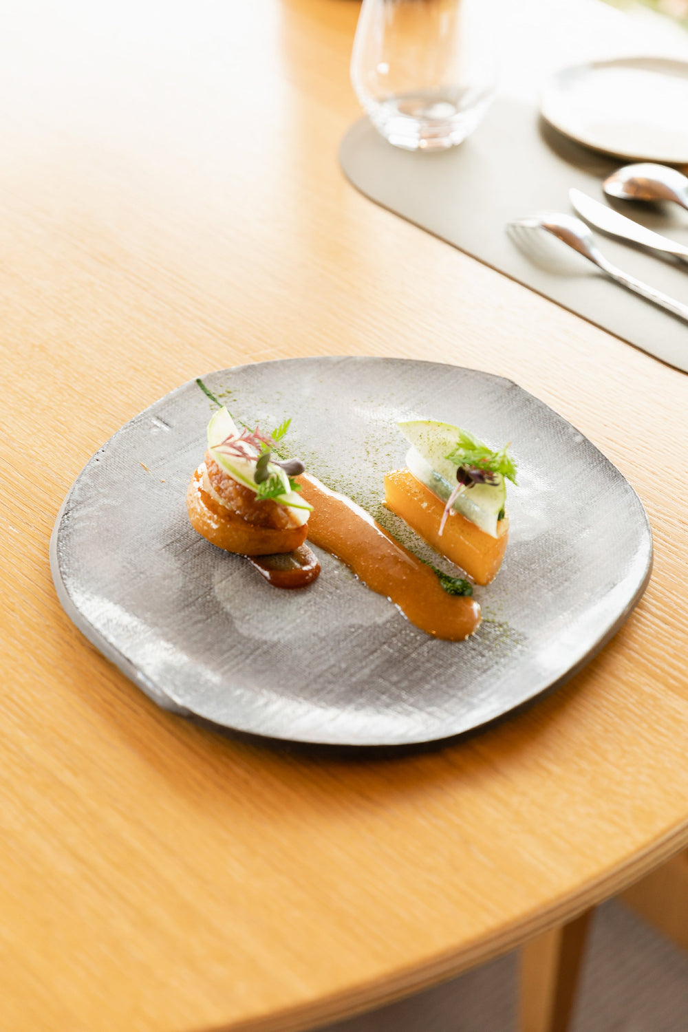 Assiette gastronomique élégante avec des morceaux de chou-rave finement disposés, nappés d'une sauce au vinaigre de cidre, garnis de fines herbes fraîches, présentée sur une table en bois clair dans un cadre raffiné.