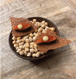 Amuse-bouche délicat sur une base de pois chiches croquants, parfait pour éveiller les papilles avec une présentation élégante.