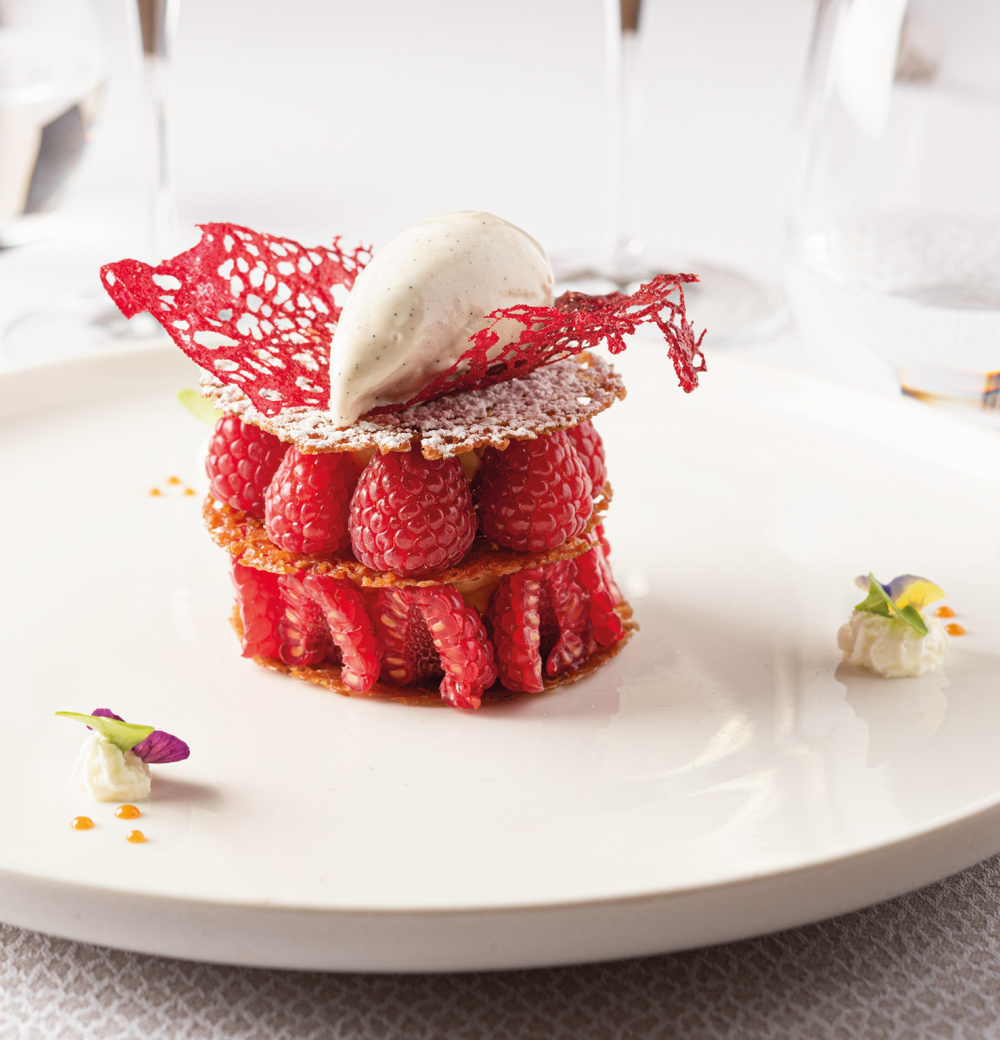 Dessert élégant aux framboises avec dentelle rouge et crème glacée sur assiette blanche