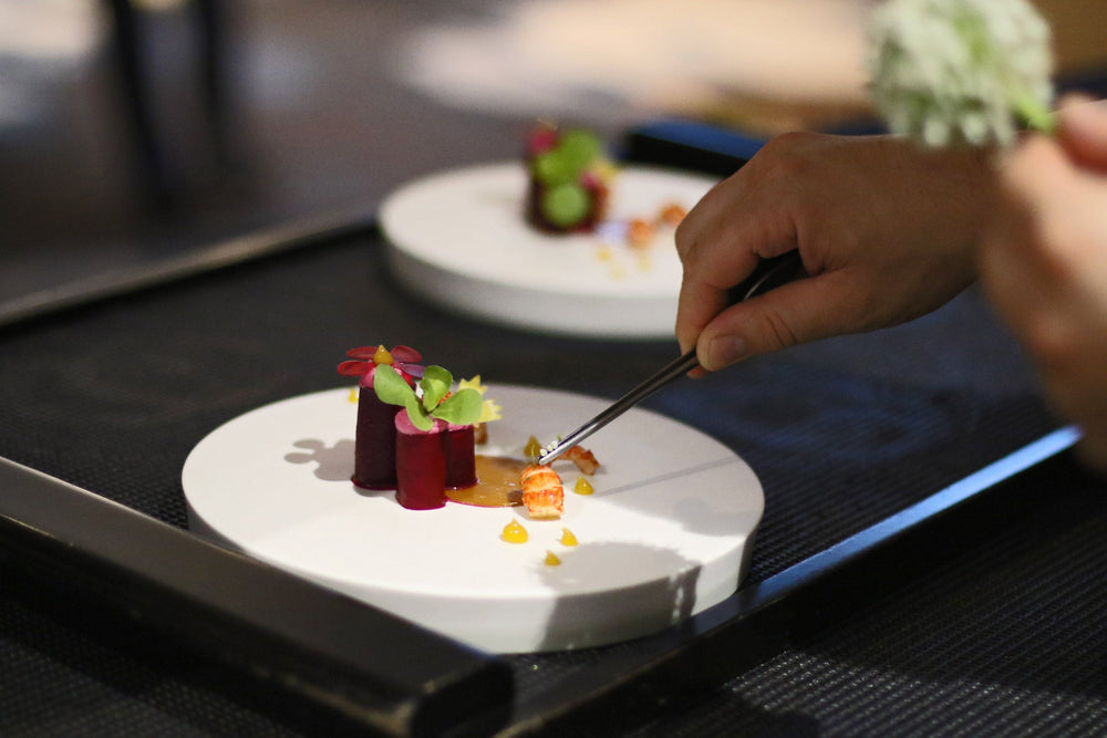 Les derniers détails sont apportés à un plat gastronomique composé de langoustine, et de légumes soigneusement travaillés